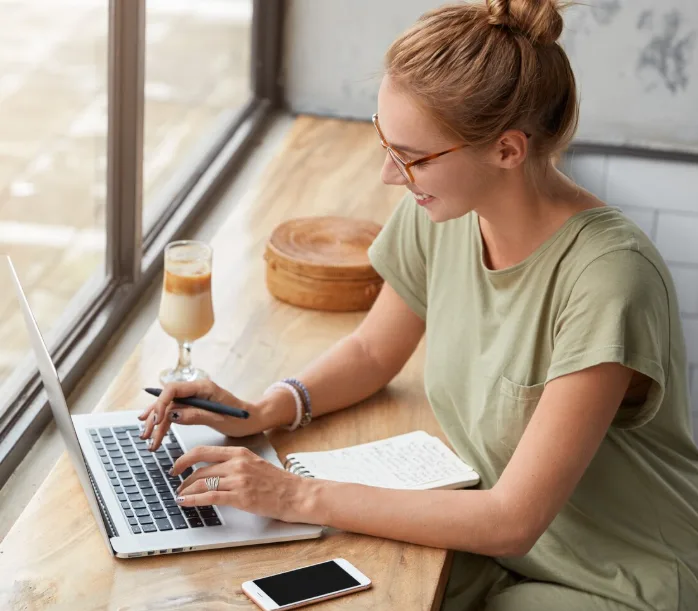 A copywriter working on a laptop by a sunny window